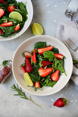 Fitness food spinach and strawberry salad in white bowls on a light table. food delivery of diet dishes. dish for spring and summer menu business lunch. the view from the top. selective focus