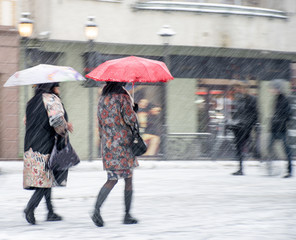 Busy city people going along the street in winter snowy day. Intentional motion blur