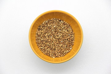 Ceramic bowl with buckwheat on a white background, top view. The concept of healthy nutrition, diets, vegetarian products. Stock photo with empty space for text and design.
