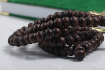 wooden praying beads on a green holy book isolated on white background