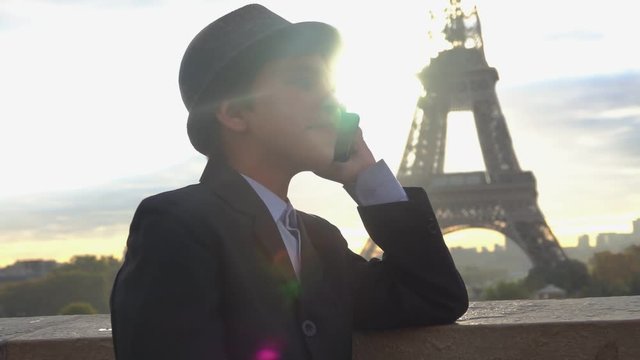 Beautiful teenager boy in a hat is talking on the phone on the background of the Eiffel tower, Paris, France