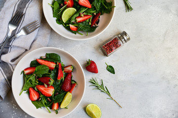 Fitness food spinach and strawberry salad in white bowls on a light table. food delivery of diet dishes. dish for spring and summer menu business lunch. the view from the top. selective focus