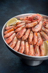 A lot of shrimp with lemon in an iron dish