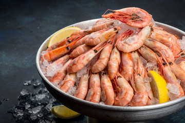 A lot of shrimp with lemon in an iron dish