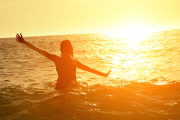 Young woman enjoying summertime in the ocean / sea water.