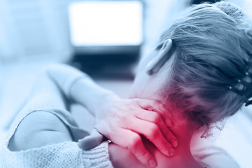 Woman working on a laptop and having neck pain / injury.