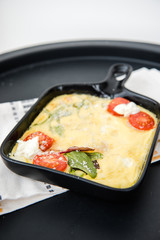 Omelette with vegetables cherry tomatoes and cheese. Italian healthy breakfast. Frittata. Scrambled eggs. Cooking omelet in a pan, ready to eat