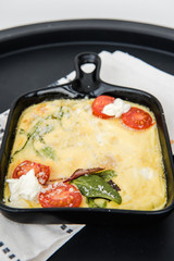 Omelette with vegetables cherry tomatoes and cheese. Italian healthy breakfast. Frittata. Scrambled eggs. Cooking omelet in a pan, ready to eat