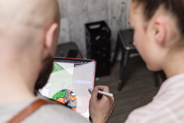 A tattoo artist show a design on a tablet to a woman
