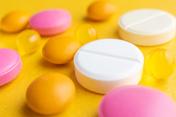 Multi-colored pills on a yellow background. The concept of protection against viruses, medicine, prevention and treatment of diseases. Macro, minimalism.