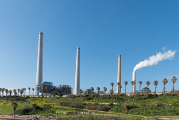Fototapeta na wymiar smoke rises from power plant chimneys against the blue sky. Hadera, Israel power plant