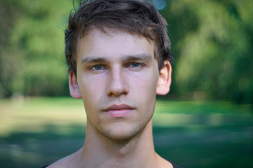 Portrait of relaxed a young man standing in a park with a plane and honest look on his face on a summer afternoon.