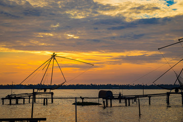 Fototapeta na wymiar Sunset from kumbalangi's beautiful backwaters. he fishing nets portray the life of people living around the coastal areas.