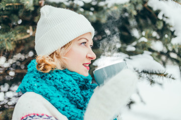 Happy attractive young caucasian blonde in winter in a snow-covered forest - a nice New Year and Christmas look