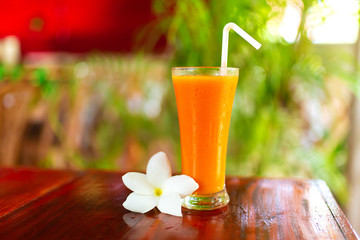 Two glass with freshly squeezed juice and frangipani flower