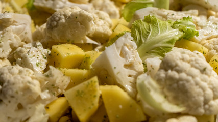 Vegan food, close-up of pan of raw vegetables sliced like ratatouille with cauliflower and potatoes oregano and rosemary before being cooked