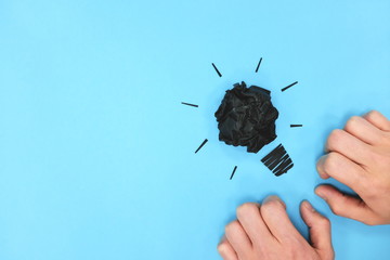 Black light bulb crumpled paper in blue background with hands flat lay. Blank mind and lack of creativity. © sulit.photos