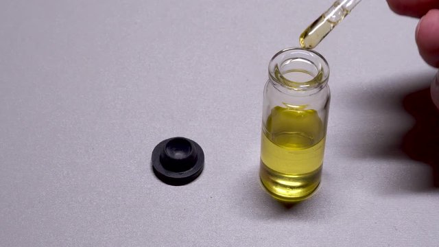 Pipette drops into glass bottle with cbd oil clos up view isolated on white. Medical cannabis concept.
