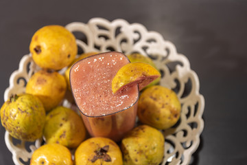 Guavas and glass of juice on white tray on marble table with dark background