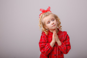 baby girl blonde folded hands begs on a white background