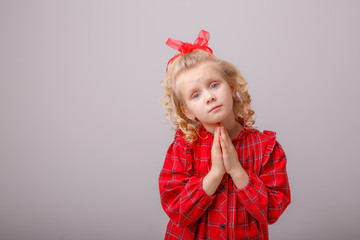 baby girl blonde folded hands begs on a white background