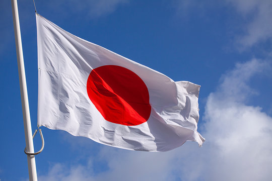 Japan flag waving in the wind against blue sky. Close up image.,