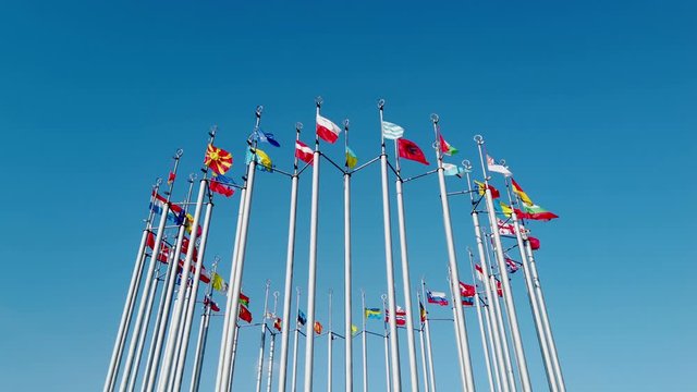 national flags of different countries on flagpoles against the blue sky