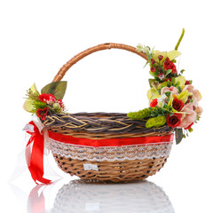 Fototapeta na wymiar Wicker basket with red and pink flowers, greens and net. Decorated in a rustic style on white background