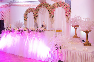 The Presidium of the newlyweds at the wedding, a table for the bride and groom. Banquet decor. Wedding presidium in restaurant. Banquet table for newlyweds. Luxury wedding decor