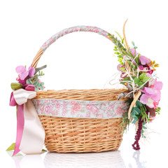 Fototapeta na wymiar Basket is decorated in pink. Decor with flowers and wide color ribbon. Isolated on a white background