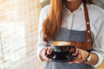 A waitress holding and serving a cup of hot coffee in cafe