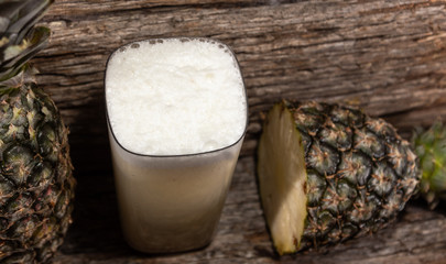 Natural juice and fresh fruits of Pineapple (Ananas comosus) on woody background