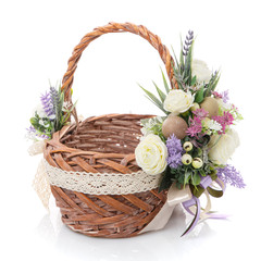 Fototapeta na wymiar Wicker brown basket decorated with delicate colored flowers of pastel colors and ribbons on white background