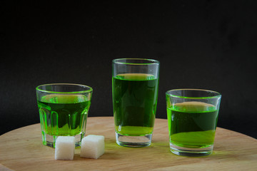 Strong alcohol. three shot glasses with absinthe, white sugar. on a wooden board
