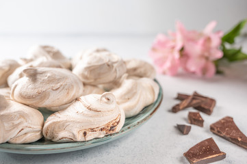 Homemade eggs dessert meringue on a plate on a light background. Next to pink flower and pieces of...