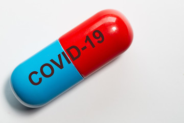 symbolic photo of a pill in blue red with the technical term for the corona virus COVID-19