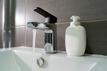 Close up on the sink faucet at home in the bathroom pouring water the water is flowing from the tap