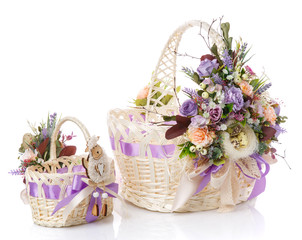 Fototapeta na wymiar Easter baskets with handmade ornaments, one of them children's. Baby little Easter basket with lamb. Decor with various flowers and greens with purple ribbon.