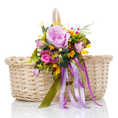 Fototapeta na wymiar Floral composition with purple flowers, greenery and ribbons hanging on the handle of a wicker basket on white background