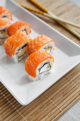 Traditional fresh Japanese sushi rolls with salmon on a white plate.