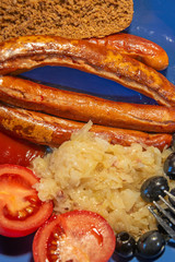 German traditional simple meal: grilled sausages, sauerkraut and bread, details, closeup