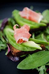 Avocado sandwich with jamon. Toasted bread for healthy breakfast or snack, copy space. Spanish tapas. Italian brushetta. Vegan avocado sandwich top view close-up