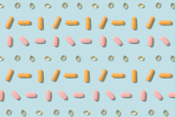 Colorful capsule pills and tablets pattern on a blue background. Cover, pharmacy, drugs, medicine backdrop. Top view