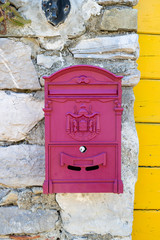 Old vintage magenta metal mail box with crest in Italy Europe ona sunny summer day front view