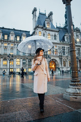 Elegant girl stands alone in the town square near the city hall. Attractive girl traveler with...