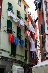 Fototapeta na wymiar Colourful old buildings with clothing hanging lines in a small town Liguria region ofItaly on a slightly overcast summer day