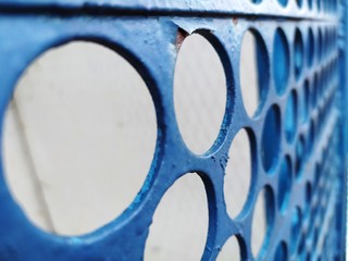 Iron blue fence with round holes, peeling paint, and under it rust. Abstract background or texture