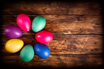 Close-up of multicolored traditional easter eggs painted in blue, red, purple, yellow colors on wooden table. Macrophotography. Vibrant easter festive background. Text space.