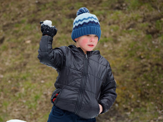 winter fun. cheerful child in a hat plays snowballs
