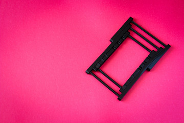 black folding phone holder, on a pink  background